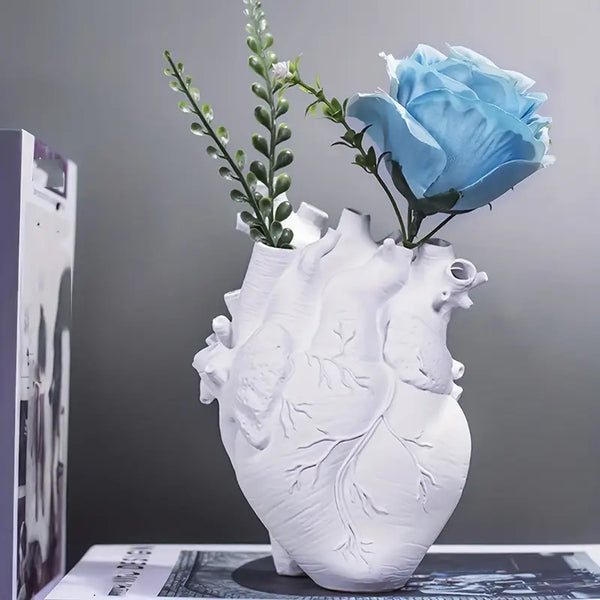 White heart-shaped vase with floral arrangement on a gray background