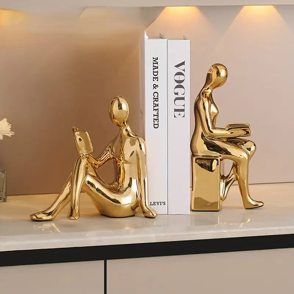 Gold decorative figures on a shelf with a 'Vogue' book in the background decor aura works