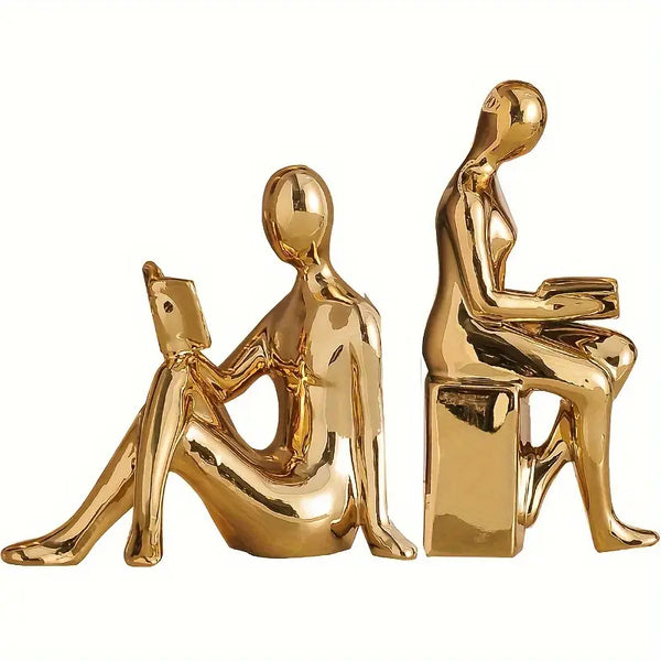 Gold ceramic sculptures of a woman reading and a man using a laptop on a white background decor aura works