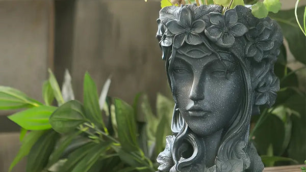 Decorative planter shaped like a face with floral details on a wooden surface. auraworks vase