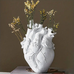 White heart-shaped vase with floral arrangement on a brown background