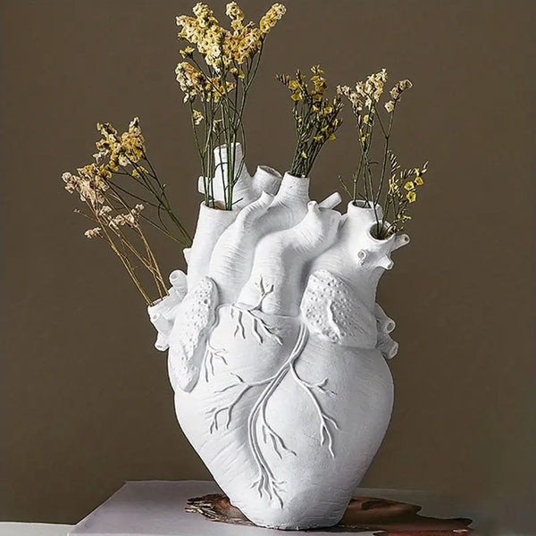 White heart-shaped vase with floral arrangement on a brown background