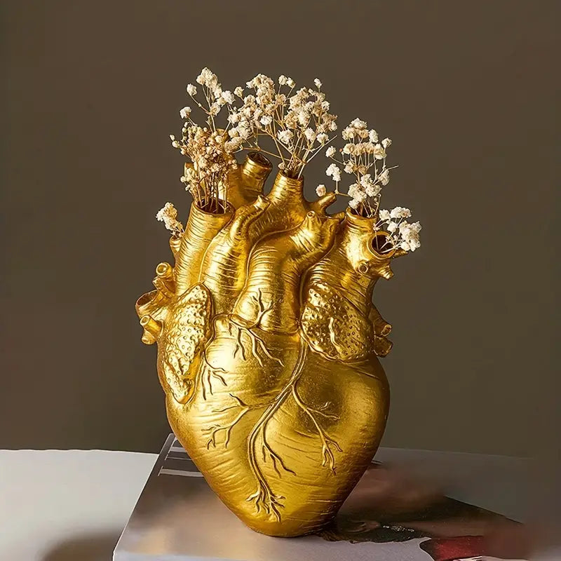Three heart-shaped vases in gold, red, and white on a gray surface with a dark background. auraworks deccor