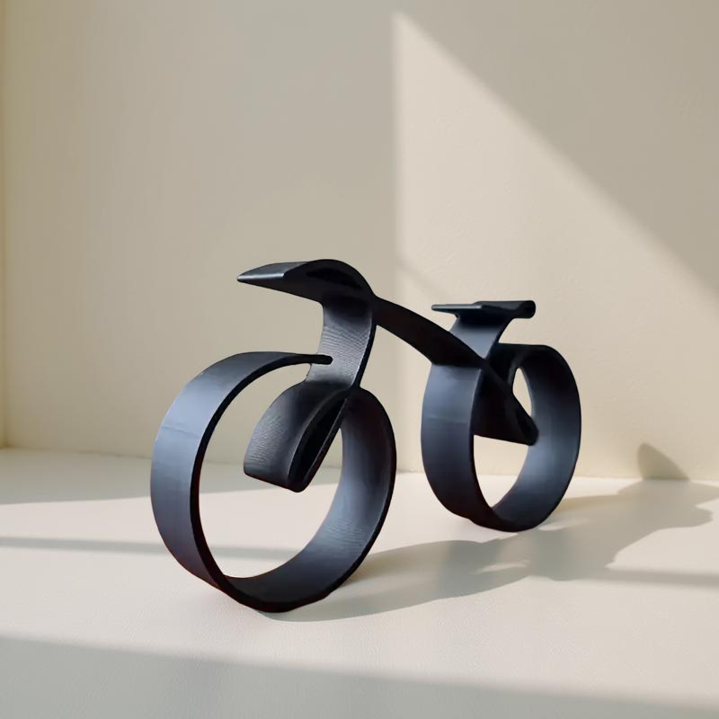 Black metal sculpture of a stylized bicycle on a light background decor aura works