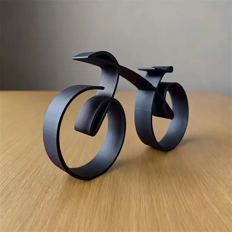 Black metal sculpture of a stylized bicycle on a light background decor aura works
