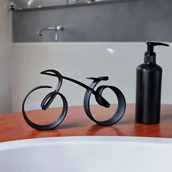 Black bicycle-shaped bottle holder on a wooden surface with a black soap dispenser. decor aura works