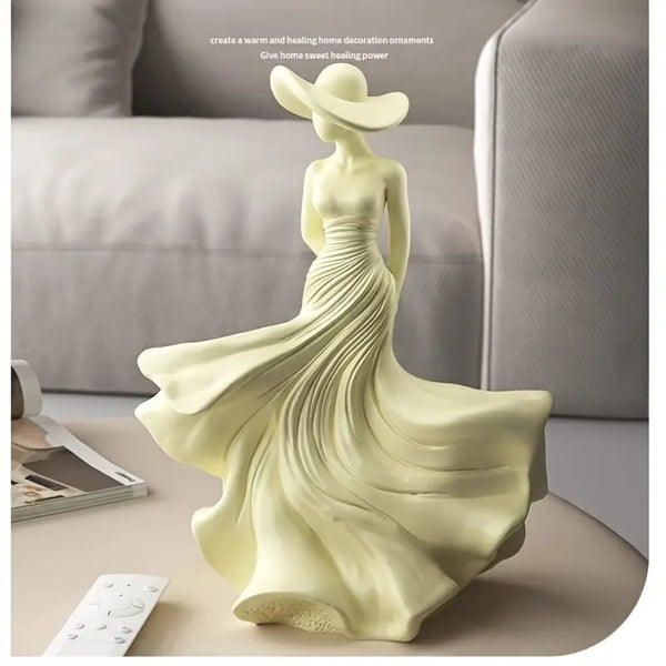 Decorative sculpture of a woman in a flowing dress on a table with a blurred sofa background