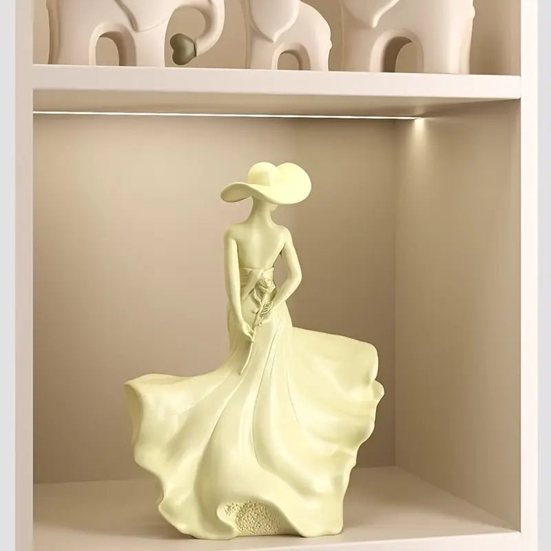 Decorative sculpture of a woman in a flowing dress on a beige shelf.
