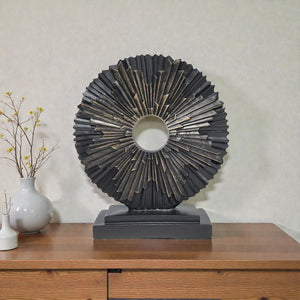Decorative sunburst sculpture on a wooden surface with a neutral background Aura Works