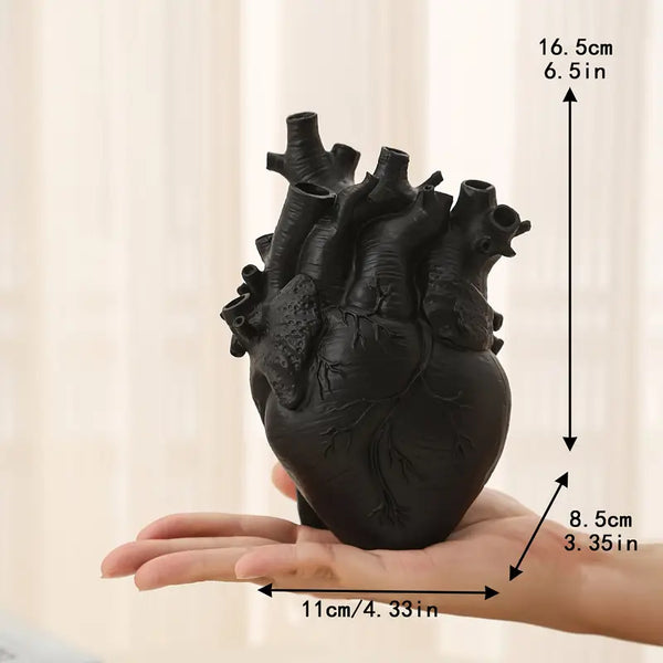 Black anatomical heart model held in a hand with measurements indicated. vase auraworks
