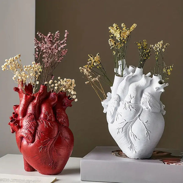 Two heart-shaped vases, one red and one white, with dried flowers on a neutral background. vase auraworks
