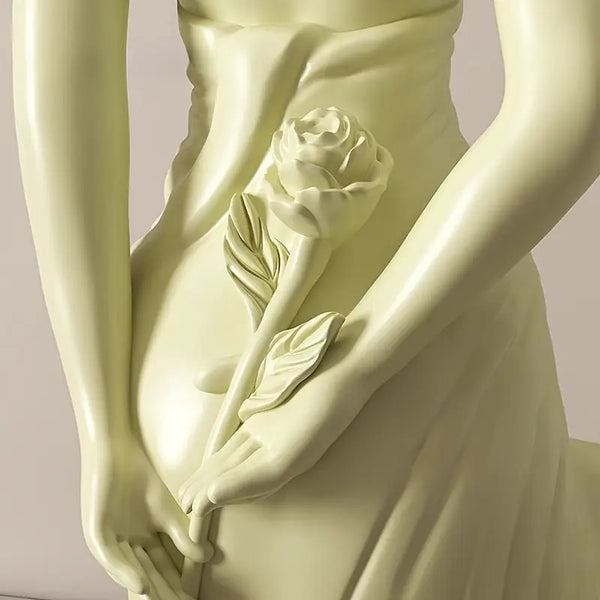 Statue of a draped figure holding a rose against a plain background