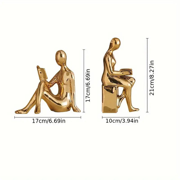 Gold sculptures of a person sitting and using a laptop, with dimensions displayed. decor aura works