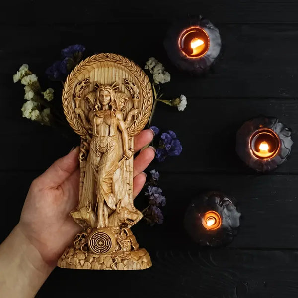 Hand holding a wooden statue with candles and flowers on a dark surface decor auraworks