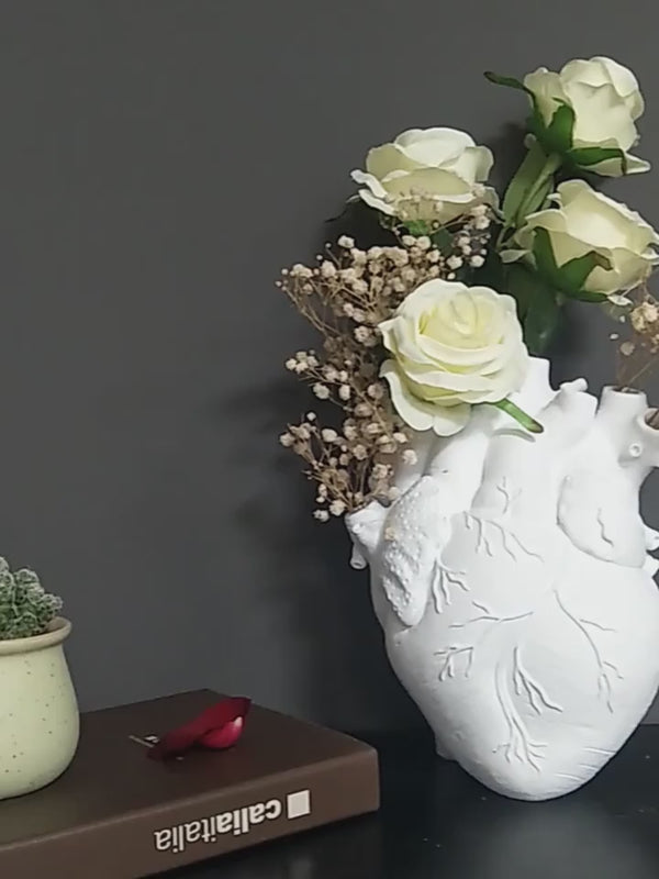 Three heart-shaped vases in gold, red, and white on a gray surface with a dark background. auraworks deccor